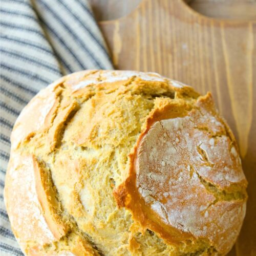 lazy-sourdough-bread-on-a-french-bread-board-next-to-striped-towel